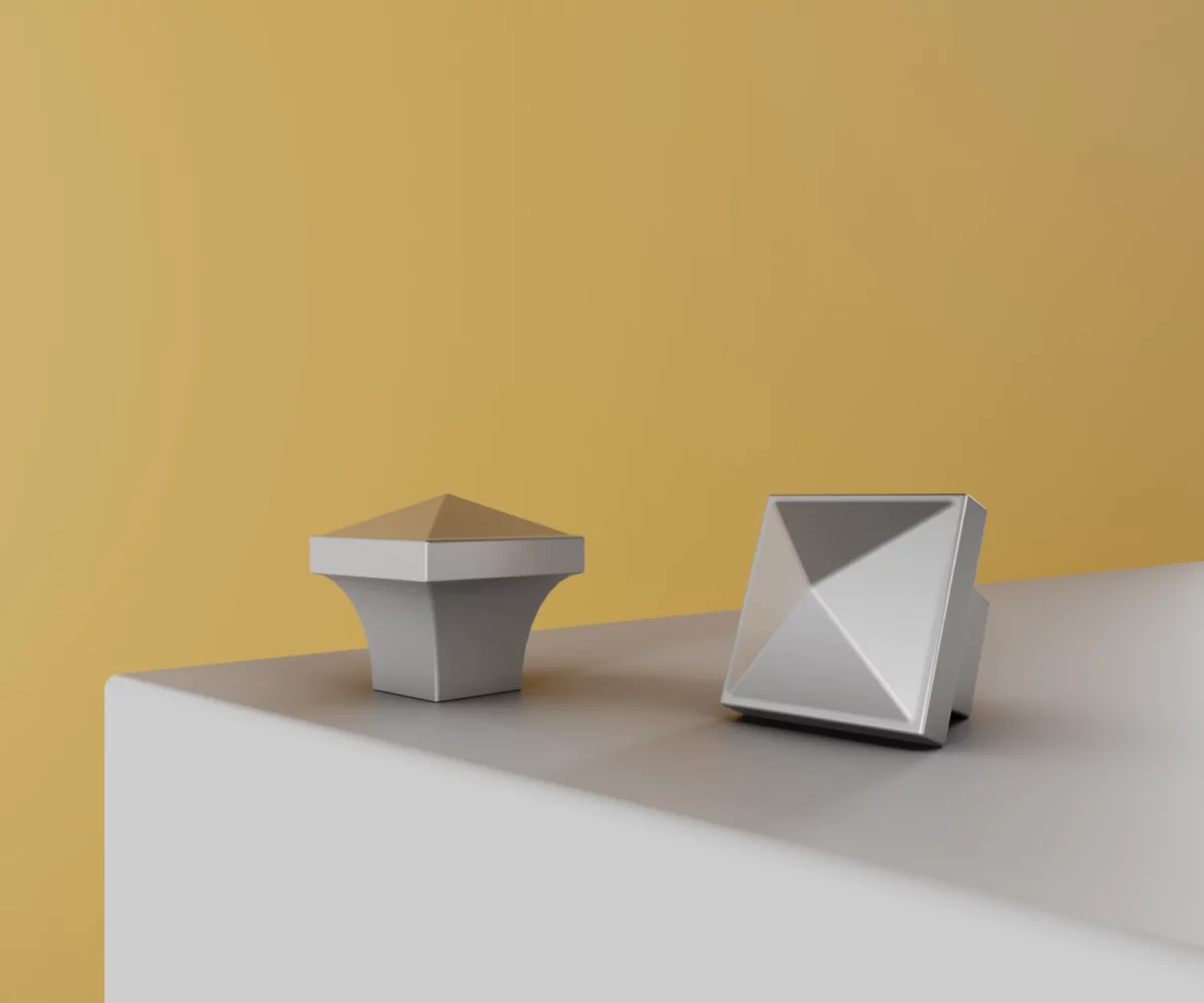 Zwei silberne Zink-Knäufe vom Typ KB-ZI-10029 auf einer weißen Fläche vor gelbem Hintergrund.