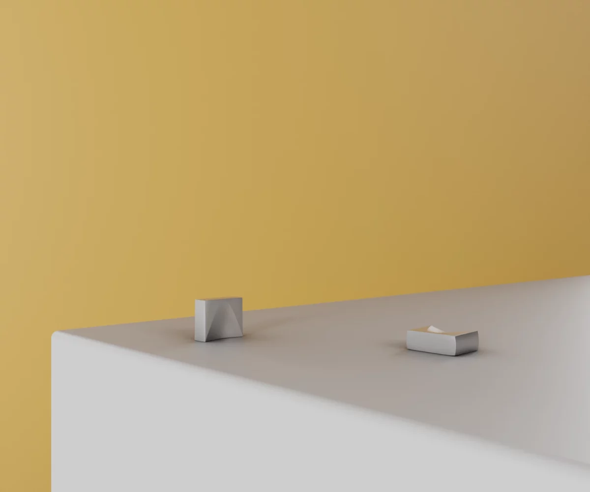 Zwei silberne Zink-Knäufe vom Typ KB-ZI-10039 auf einer weißen Fläche vor gelbem Hintergrund.