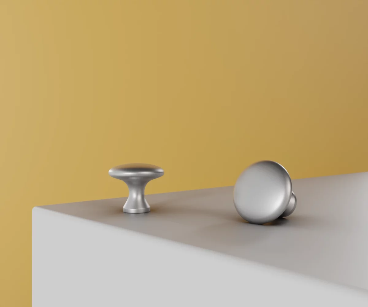 Zwei silberne Zink-Knäufe vom Typ KB-ZI-10055 auf einer weißen Fläche vor gelbem Hintergrund.