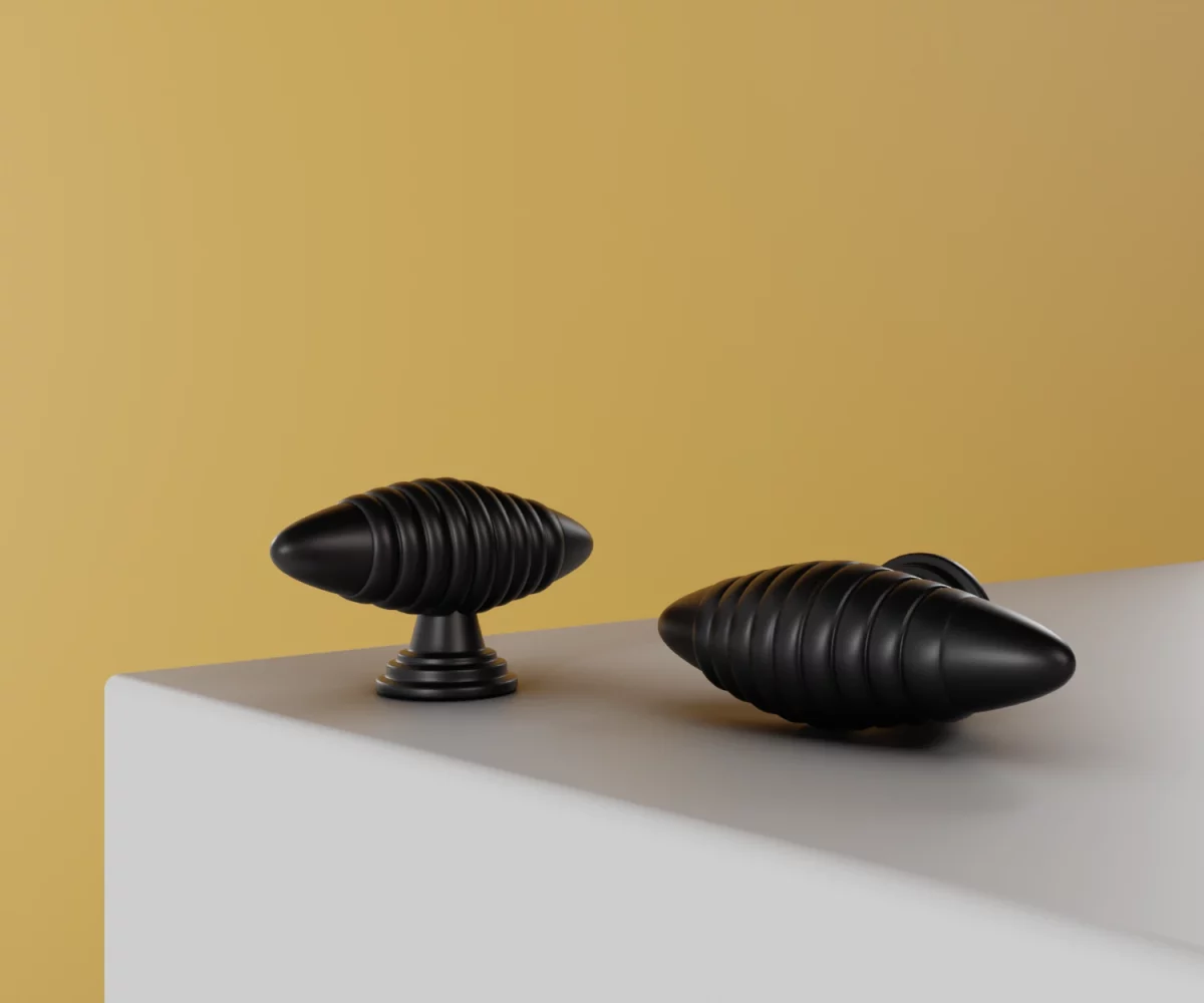 Zwei mattschwarze Zink-Knäufe vom Typ KB-ZI-10058 auf einer weißen Fläche vor gelbem Hintergrund.