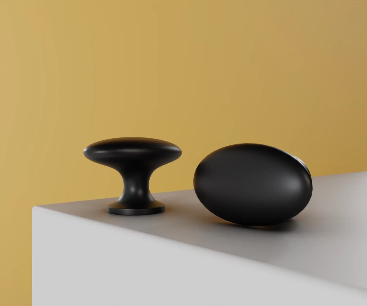 Zwei mattschwarze Zink-Knäufe vom Typ KB-ZI-10059 auf einer weißen Fläche vor gelbem Hintergrund.