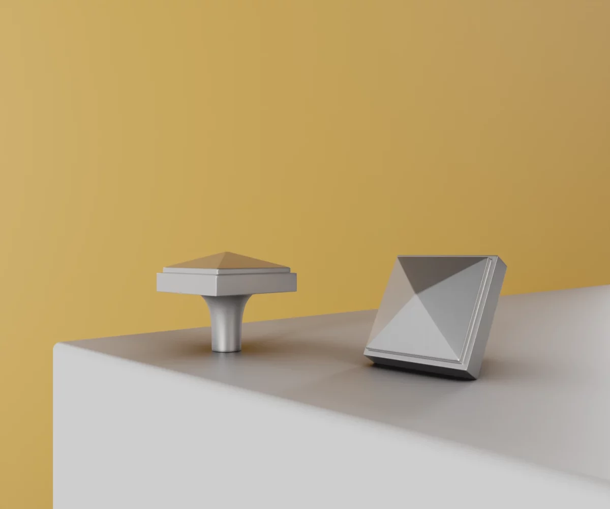 Zwei silberne Zink-Knäufe vom Typ KB-ZI-10061 auf einer weißen Fläche vor gelbem Hintergrund.