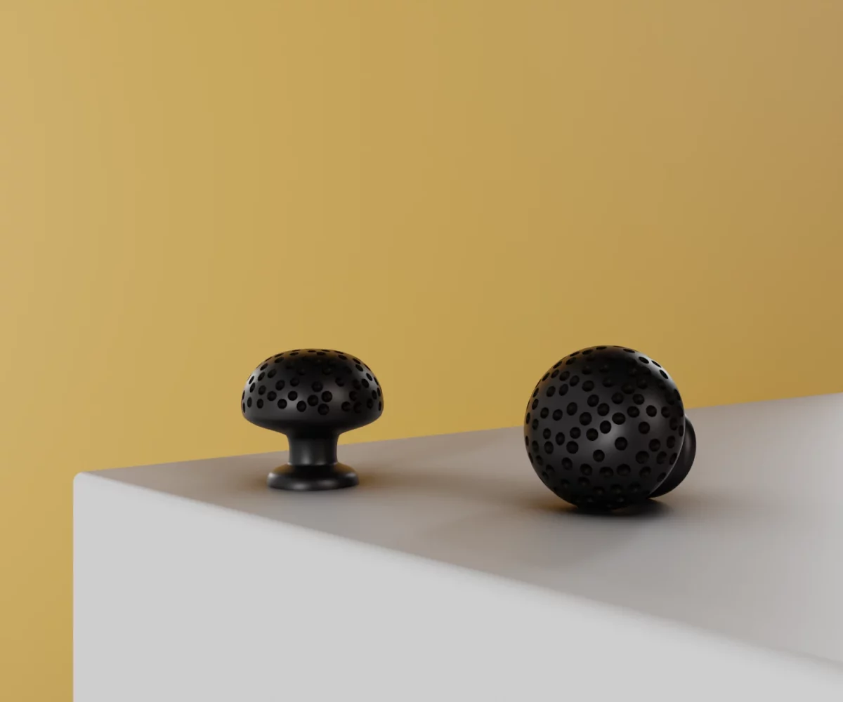Zwei mattschwarze Zink-Knäufe vom Typ KB-ZI-11033 auf einer weißen Fläche vor gelbem Hintergrund.