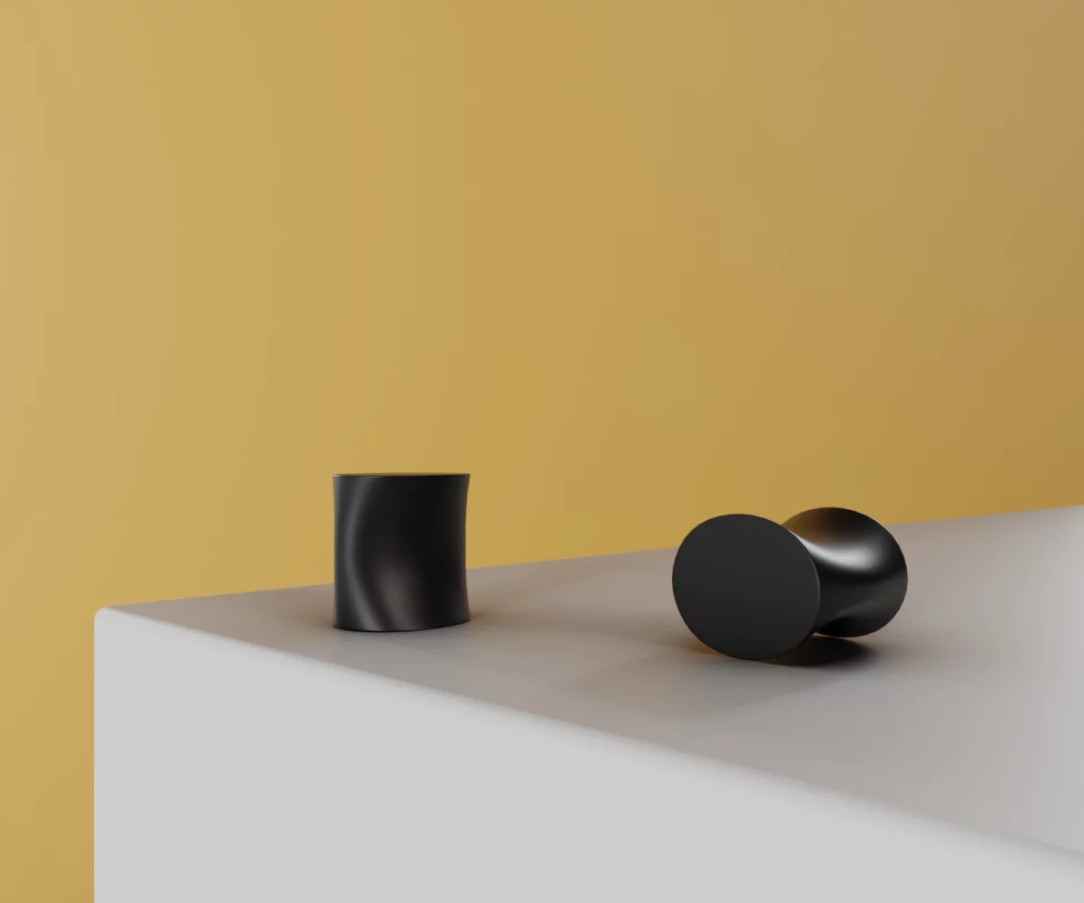 Zwei mattschwarze Zink-Knäufe vom Typ KB-ZI-11147 auf einer weißen Fläche vor gelbem Hintergrund.