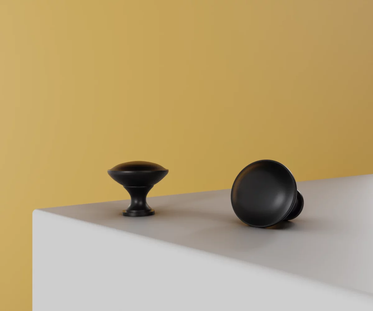 Zwei mattschwarze Zink-Knäufe vom Typ KB-ZI-11149 auf einer weißen Fläche vor gelbem Hintergrund.