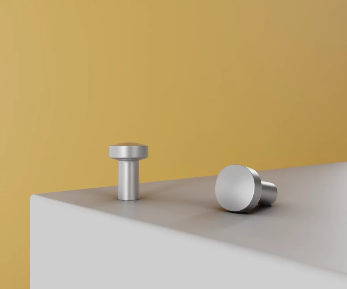 Zwei silberne Zink-Knäufe vom Typ KB-ZI-19020 auf einer weißen Fläche vor gelbem Hintergrund.