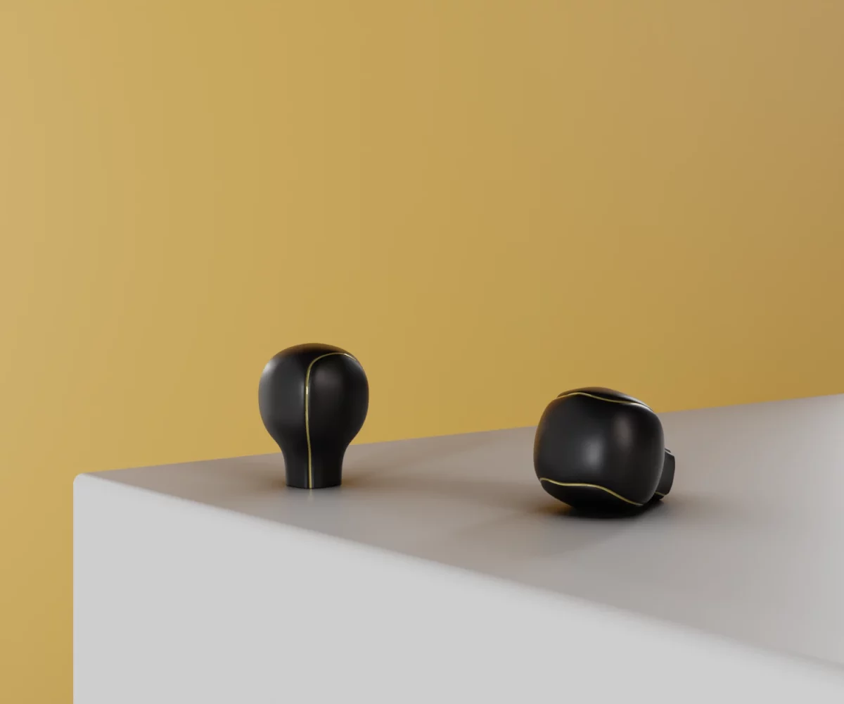 Zwei mattschwarze Zink-Knäufe mit goldenen Akzentlinien vom Typ KB-ZI-19026 auf einer weißen Fläche vor gelbem Hintergrund.