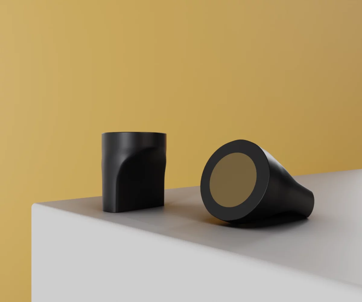 Zwei mattschwarze Zink-Knäufe vom Typ KB-ZI-19029 auf einer weißen Fläche vor gelbem Hintergrund.