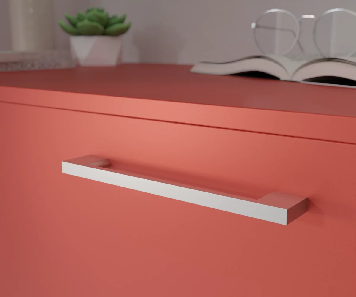 Silberfarbener Aluminium-Möbelgriff HA-AD-10031 mit klarer, kantiger Formgebung. Der Griff besteht aus einem rechtwinkligen, länglichen Bügel mit flachen Seitenflächen und einem durchgehend rechteckigen Querschnitt. Die Enden schließen rechtwinklig an und bilden eine sachlich-lineare Silhouette ohne Rundungen. Der Griff ist mittig auf einer korallenroten Schublade montiert dargestellt. Im Hintergrund unscharf dargestellt, befinden sich auf der rechten Seite ein aufgeschlagenes Buch mit einer Brille, die auf diesem Buch liegt. Auf der linken Seite befindet sich eine kleine grüne Pflanze in einem kleinen weißen Topf, links daneben eine hohe Vase und vor dieser Vase liegen zwei Bücher.