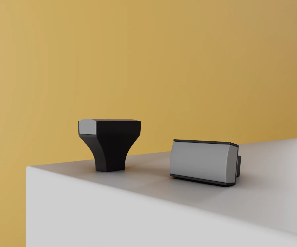 Zwei mattschwarze Aluminium-Knäufe mit gräulichem Einsatz vom Typ KB-AD-11148 auf einer weißen Fläche vor gelbem Hintergrund.