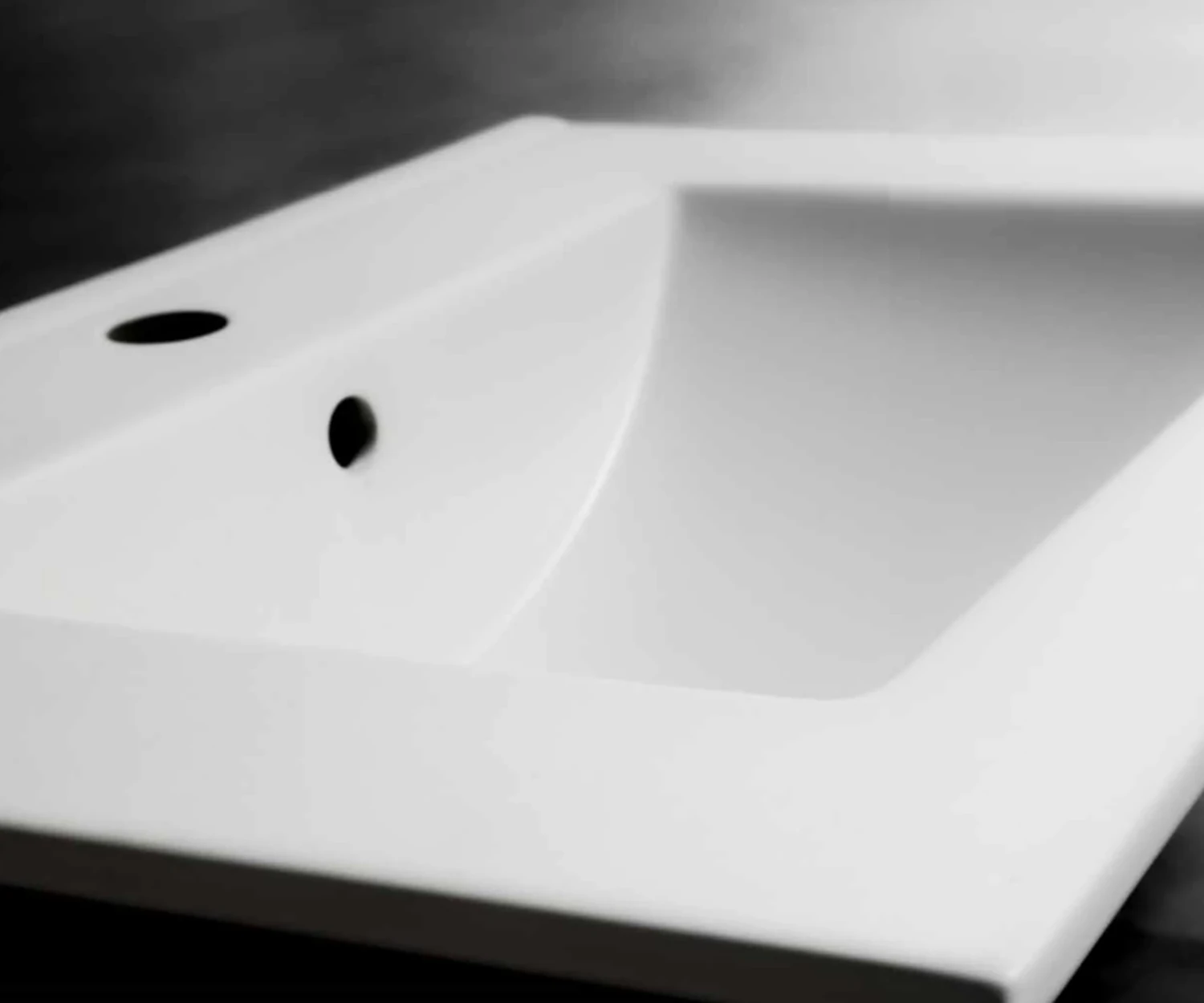 Nahaufnahme eines Waschbeckens ohne Armatur auf einem anthrazitfarbenen Hintergrund.